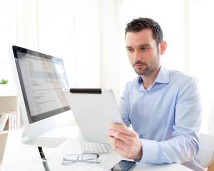 View of a Young business man working at home on his tablet
