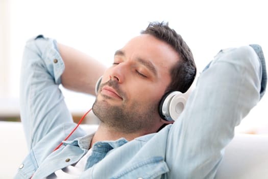 View of a Young relaxed man listening music in a sofa