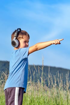 Cute 6 year old boy listening to music on headphones in nature