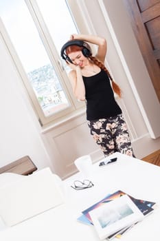 Happy young woman with headphones listening to music in living room