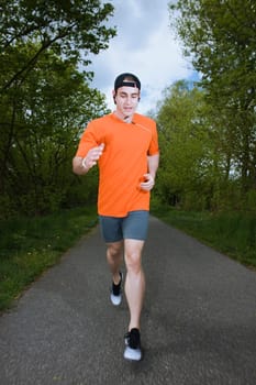 Frontal full-body view of a young man in a sports dress happily running towards the camera