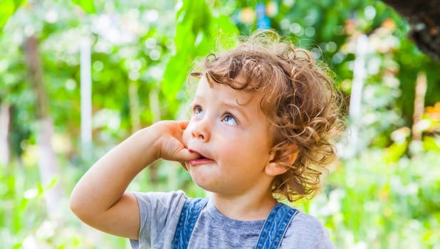 Portrait of 1 year old baby boy sucking his finger outdoor.