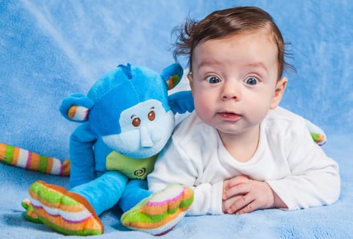 Portrait of an adorable smiling baby playing with a monkey toy.