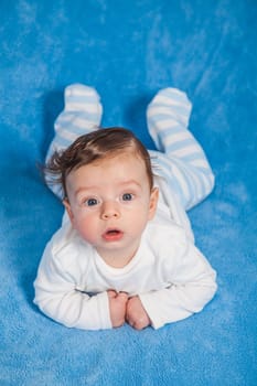 Portrait of an adorable baby boy on a blue blanket.