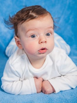 Portrait of an adorable baby boy on a blue blanket.