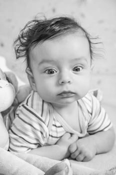 Portrait of an adorable smiling baby playing with a monkey toy.