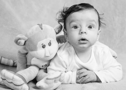 Portrait of an adorable smiling baby playing with a monkey toy.