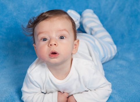 Portrait of an adorable baby boy on a blue blanket.