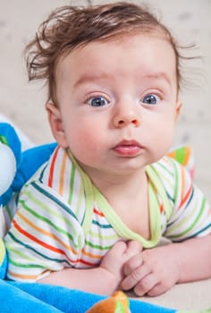 Portrait of an adorable smiling baby playing with a monkey toy.