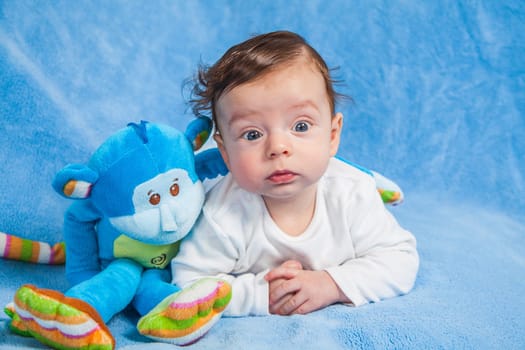 Portrait of an adorable smiling baby playing with a monkey toy.