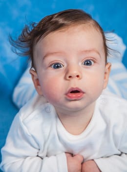 Portrait of an adorable baby boy on a blue blanket.