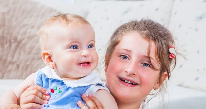 Big sister holding her 1 year old baby sister.