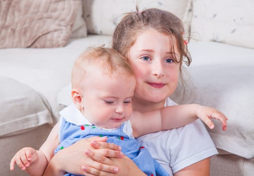 Big sister holding her 1 year old baby sister.