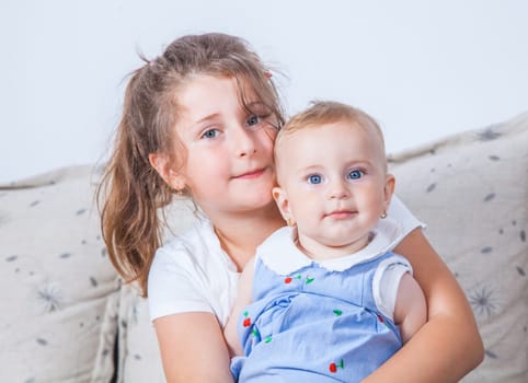 Big sister holding her 1 year old baby sister.