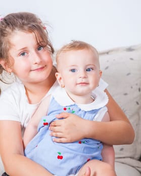 Big sister holding her 1 year old baby sister.