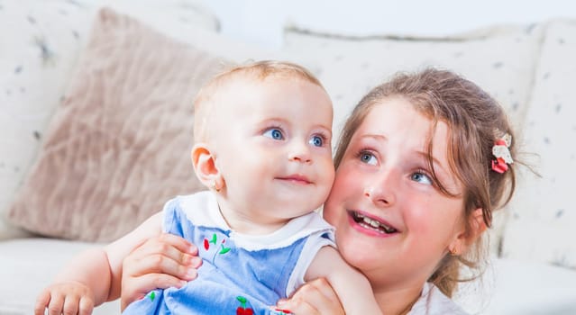 Big sister holding her 1 year old baby sister.