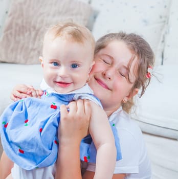 Big sister holding her 1 year old baby sister.
