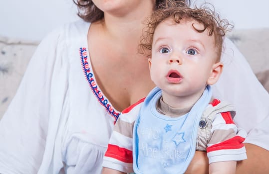 Portrait of 7 months old baby boy in woman's arms.