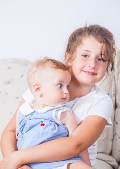 Big sister holding her 1 year old baby sister.