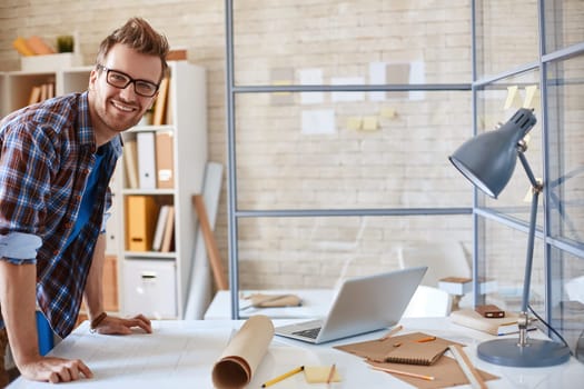 Happy young employee looking at camera in office