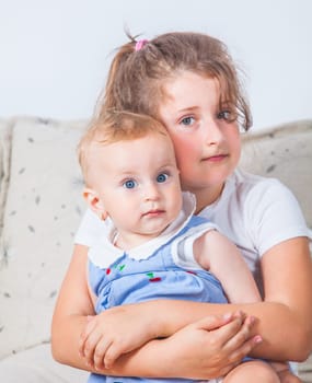 Big sister holding her 1 year old baby sister.