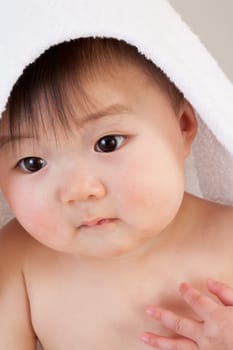 Cute Asian baby sitting with a towel over his head