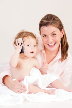 Little girl playing with her mother's phone whilst she gets dried after a bath