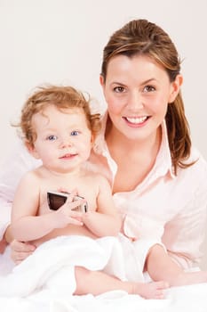 Little girl playing with her mother's phone whilst she gets dried after a bath