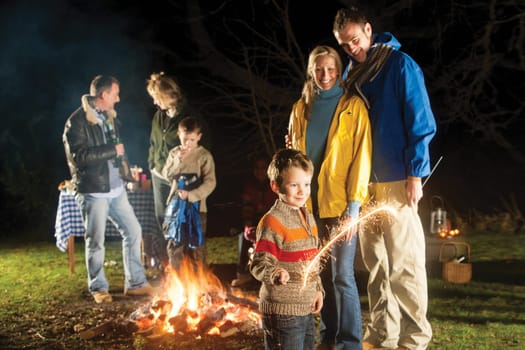 Family in garden enjoying a bonfire and playing with sparklers