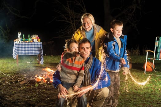 Brothers playing with sparklers in the garden with their mother and father