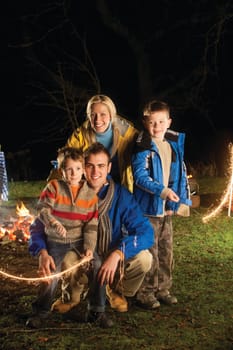 Brothers posing with sparklers on bonfire night with their parents
