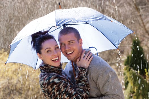 Young couple laughing in the rain under an umbrella