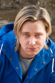Attractive young man sitting outside. He is looking pensively at the camera.