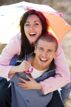 Young couple laughing in the rain under an umbrella