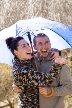 Young couple enjoying the rain under an umbrella