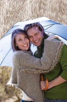 Young couple smiling under an umbrella in the rain