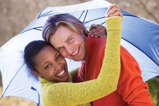 Young couple laughing in the rain under an umbrella