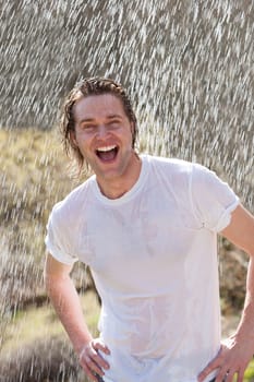 An attractive young man having fun in the rain without an umbrella