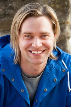Attractive young man sitting outside. He is smiling at the camera.
