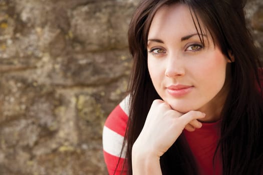 Close up portrait of an attractive young woman sitting outside smiling for the camera