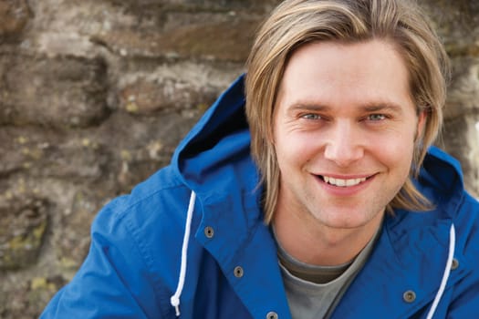 Attractive young man sitting outside. He is smiling at the camera.