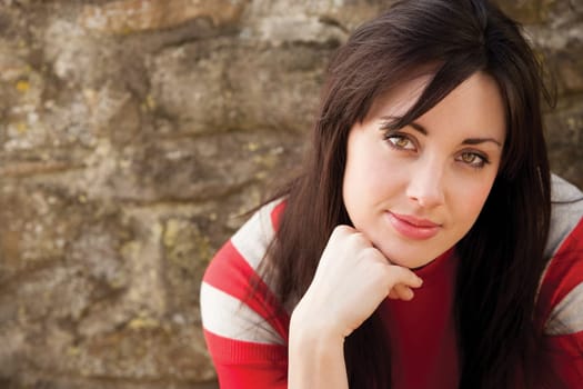 Close up portrait of an attractive young woman sitting outside smiling for the camera