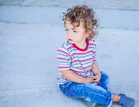 Portrait of 1 year old baby boy sitting on the ground.