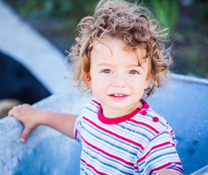 Portrait of 1 year old baby boy playing with a wheel barrow.
