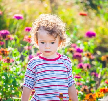 Portrait of 1 year old baby boy admiring the flowers in the garden on a sunny afternoon.