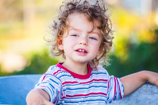 Portrait of 1 year old baby boy playing with a wheel barrow.