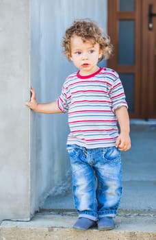 Portrait of 1 year old baby boy walking outside the house.