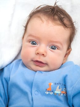 Portrait of a 2 moths old baby dressed in blue on a white blankie.