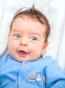 Portrait of a 2 moths old baby dressed in blue on a white blankie.
