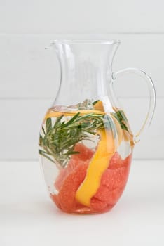 Flavoured water or infused water with red grapefruit,orange peel and rosemary in a carafe